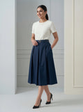 Woman wearing a white top and navy blue skirt in an indoor setting