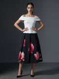 Woman wearing a white off-shoulder top and black floral skirt against a gray background