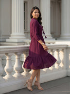 Woman in a purple dress standing in front of classical architecture