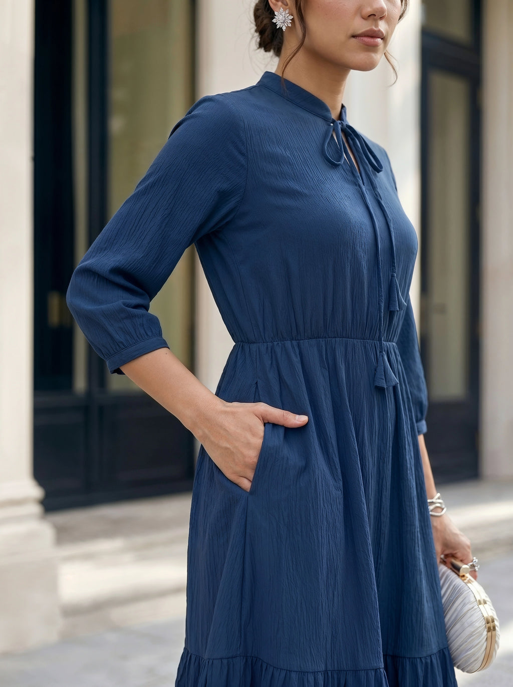 Woman wearing a blue dress standing in front of a building.