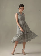 Woman wearing a sleeveless, patterned dress against a neutral background