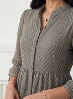 Person wearing a green and brown patterned dress with a blurred background