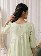 Woman wearing a light green dress with a neutral background