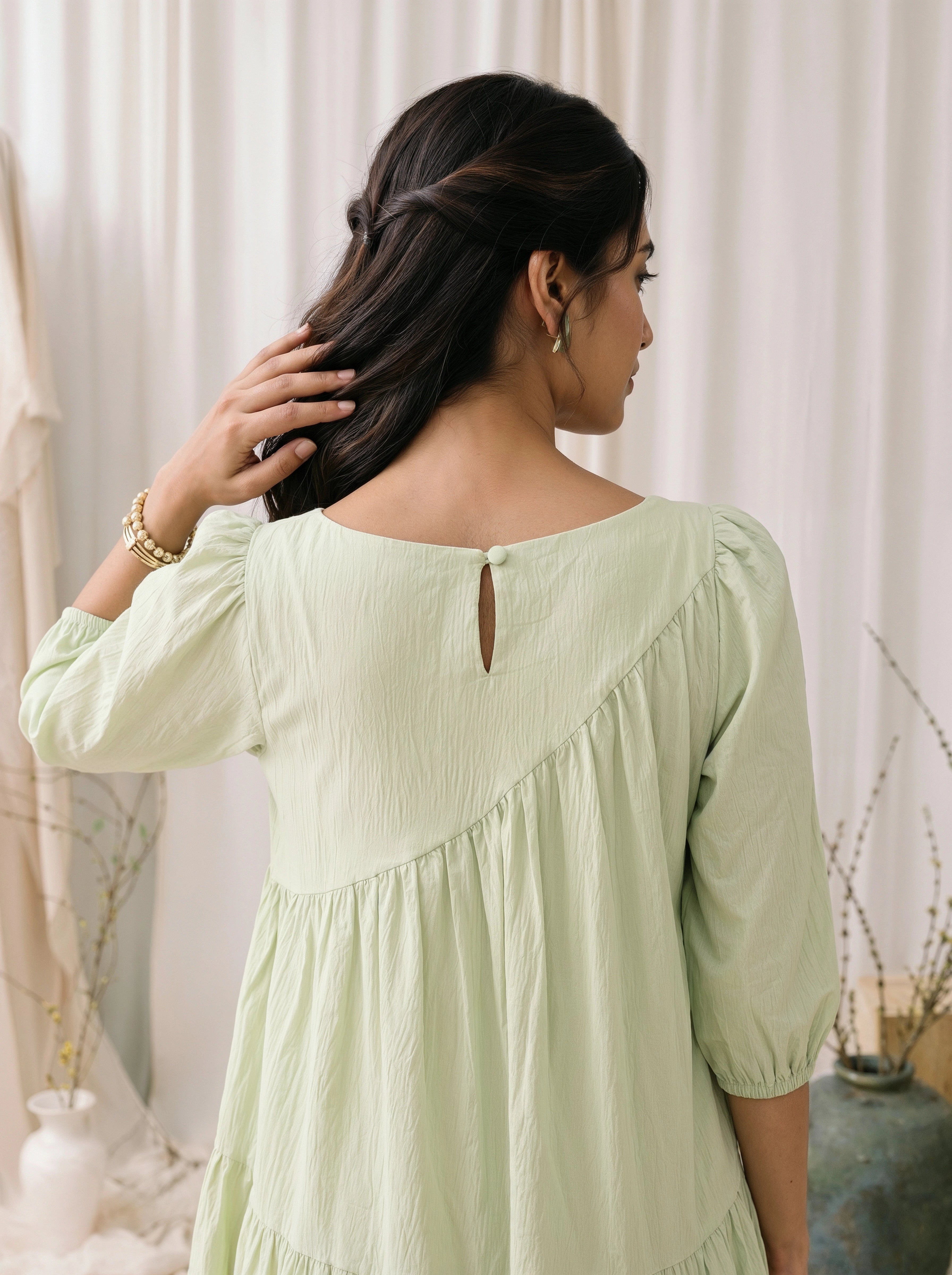 Woman wearing a light green dress with a neutral background