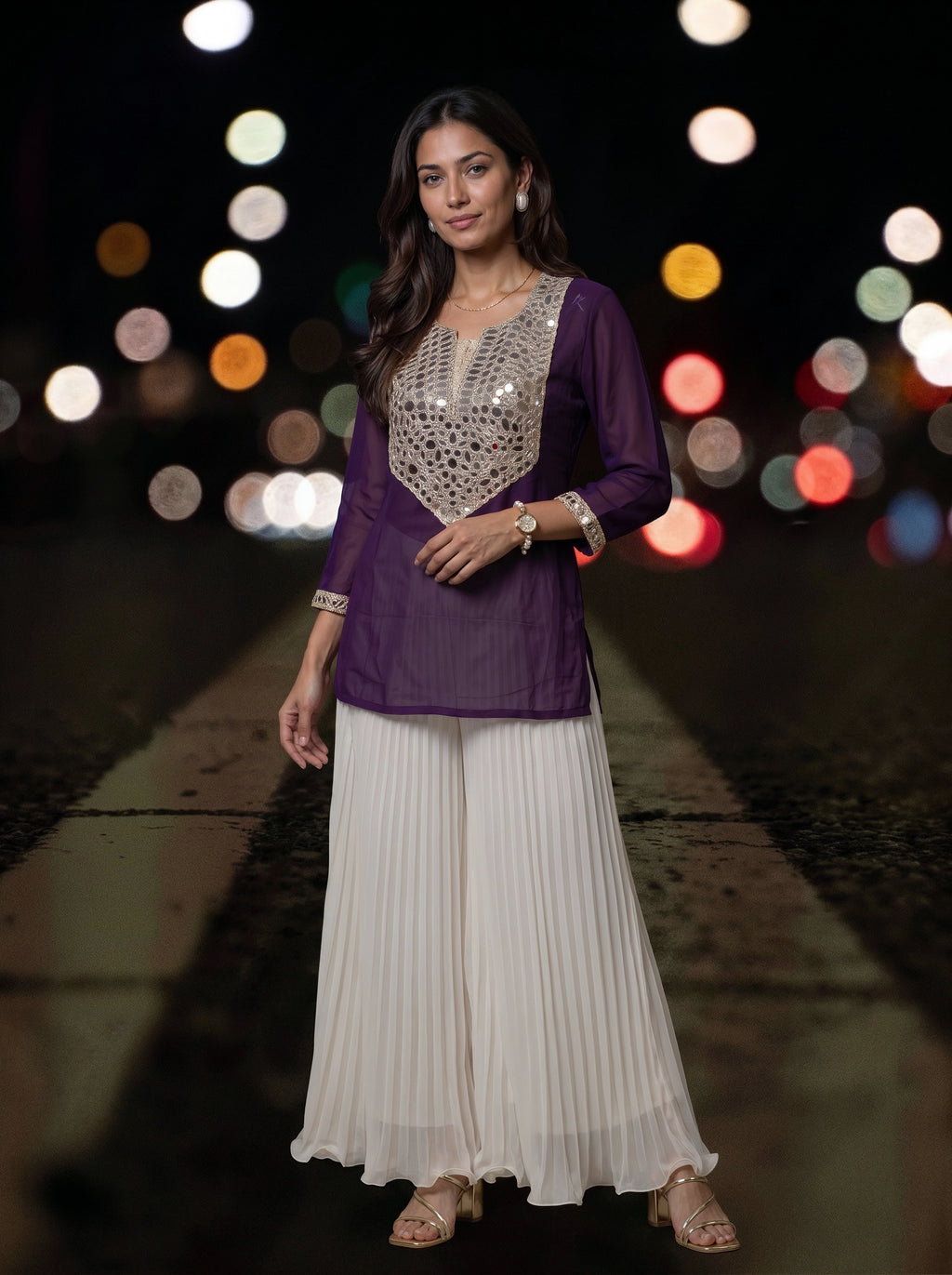 A woman modeling a purple and white traditional outfit with a heavily embellished silver sequin bodice, set against a dark background with colorful bokeh lights.