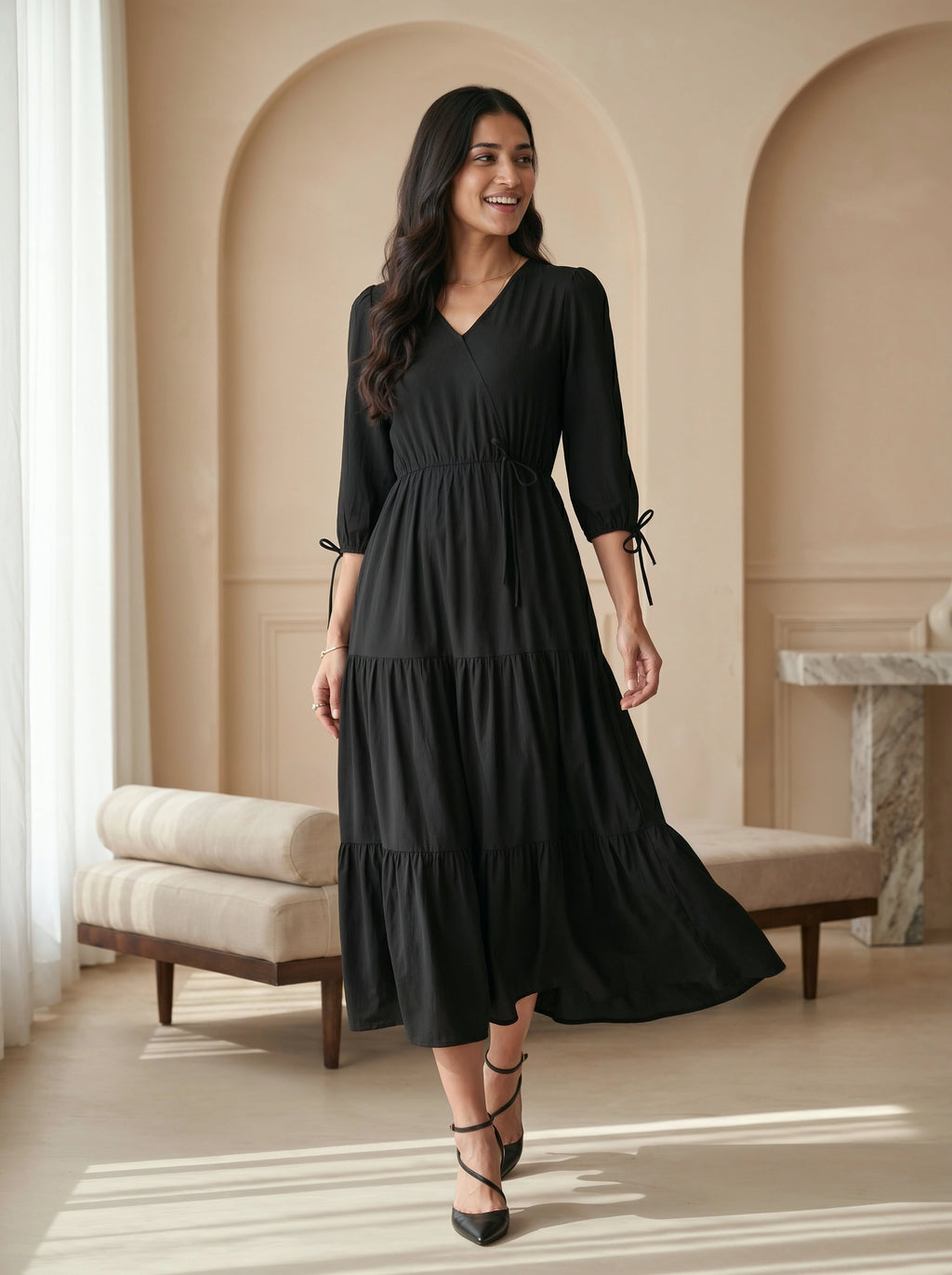 Woman wearing a black dress in an elegant room with beige walls and a striped rug.