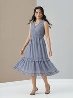 Woman wearing a blue dress standing against a neutral background