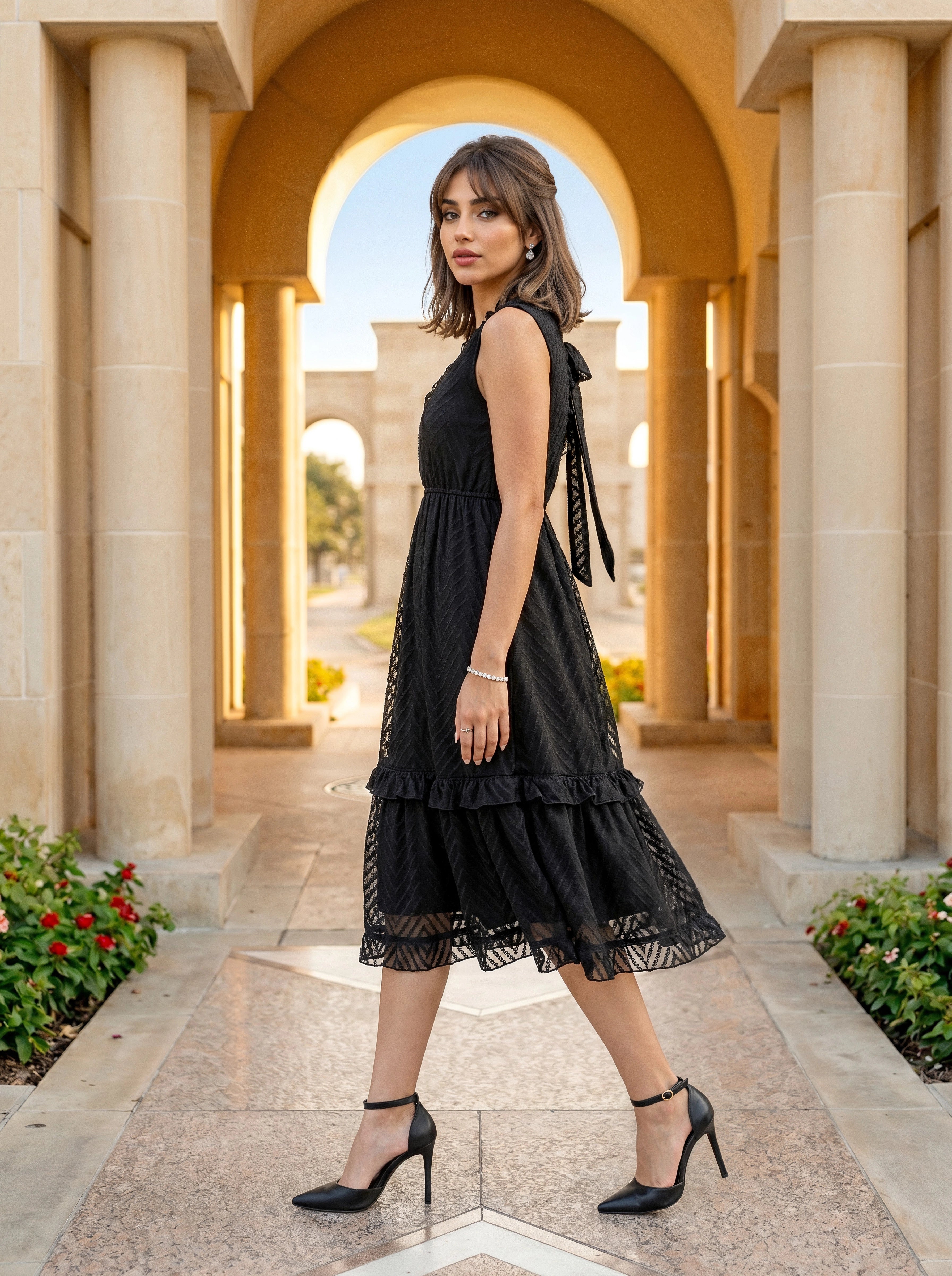 Woman in a black dress standing in front of classical architecture with columns and arches.