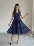 Woman wearing a navy blue dress in a room with a neutral background