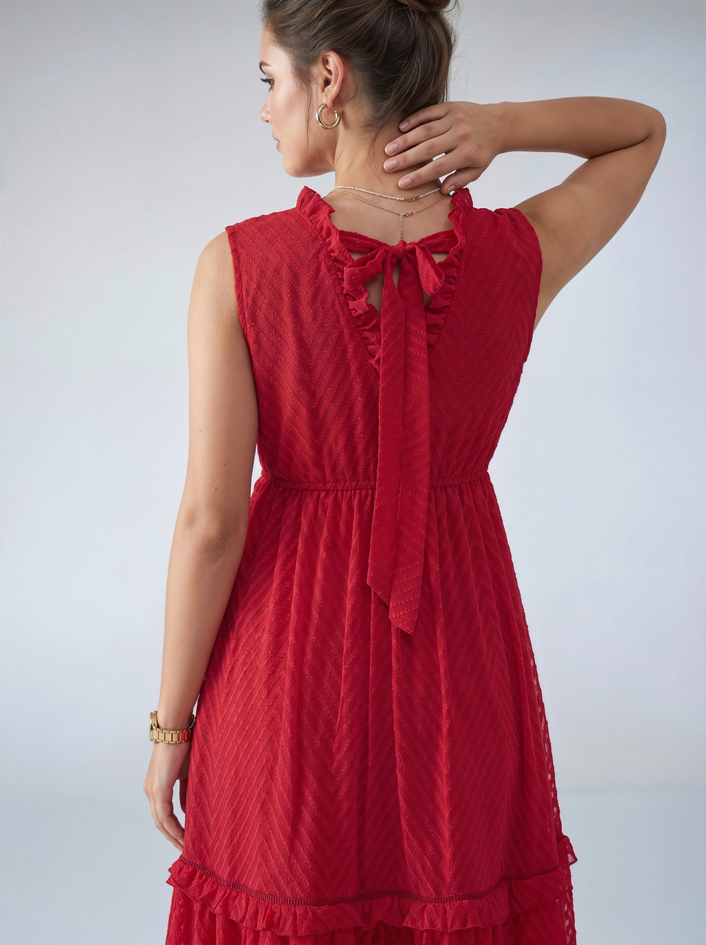 Woman wearing a red dress with a textured pattern on a plain background