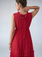 Woman wearing a red dress with a textured pattern on a plain background