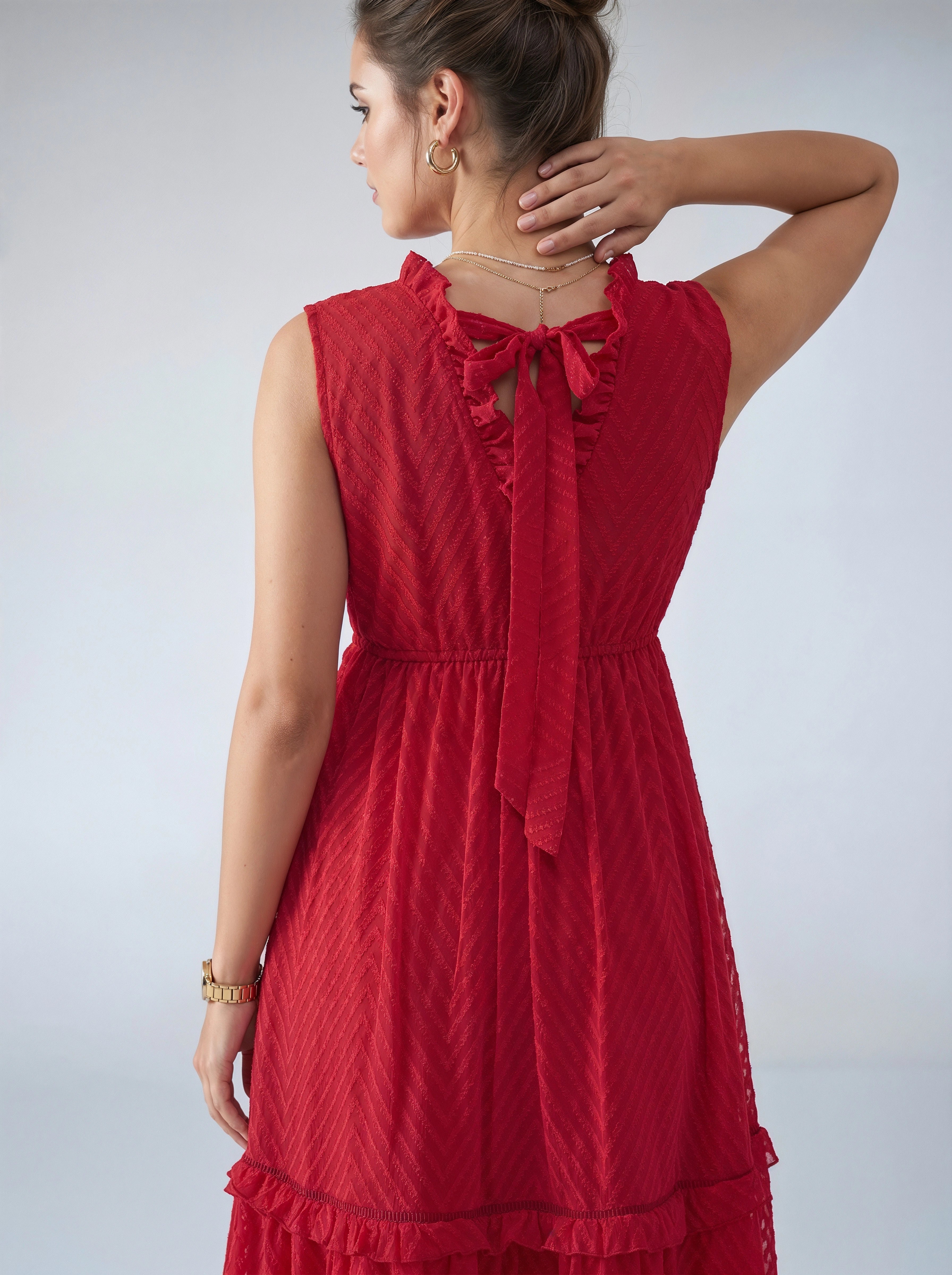 Woman wearing a red dress with a textured pattern on a plain background