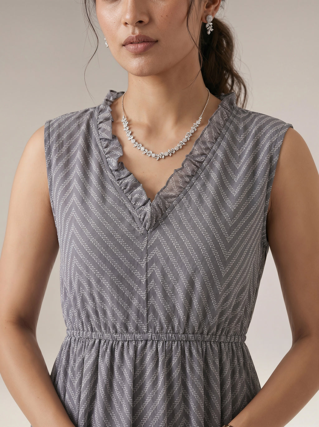 Woman wearing a gray patterned dress with a neutral background