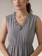 Woman wearing a gray patterned dress with a neutral background