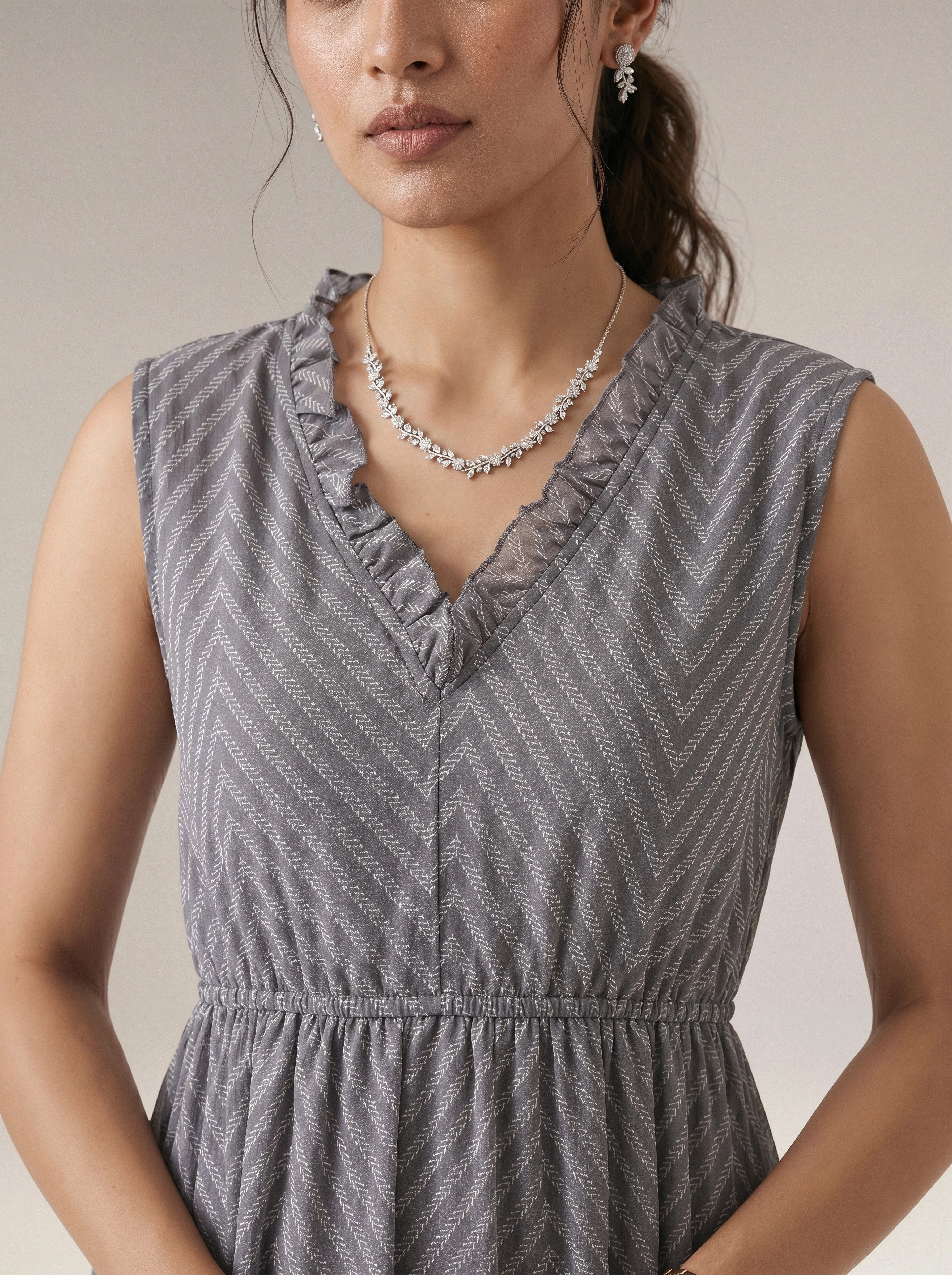 Woman wearing a gray patterned dress with a neutral background