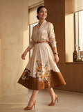 Woman wearing a beige dress with floral embroidery in a warm-toned room.