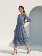 Woman wearing a blue dress standing against a light background