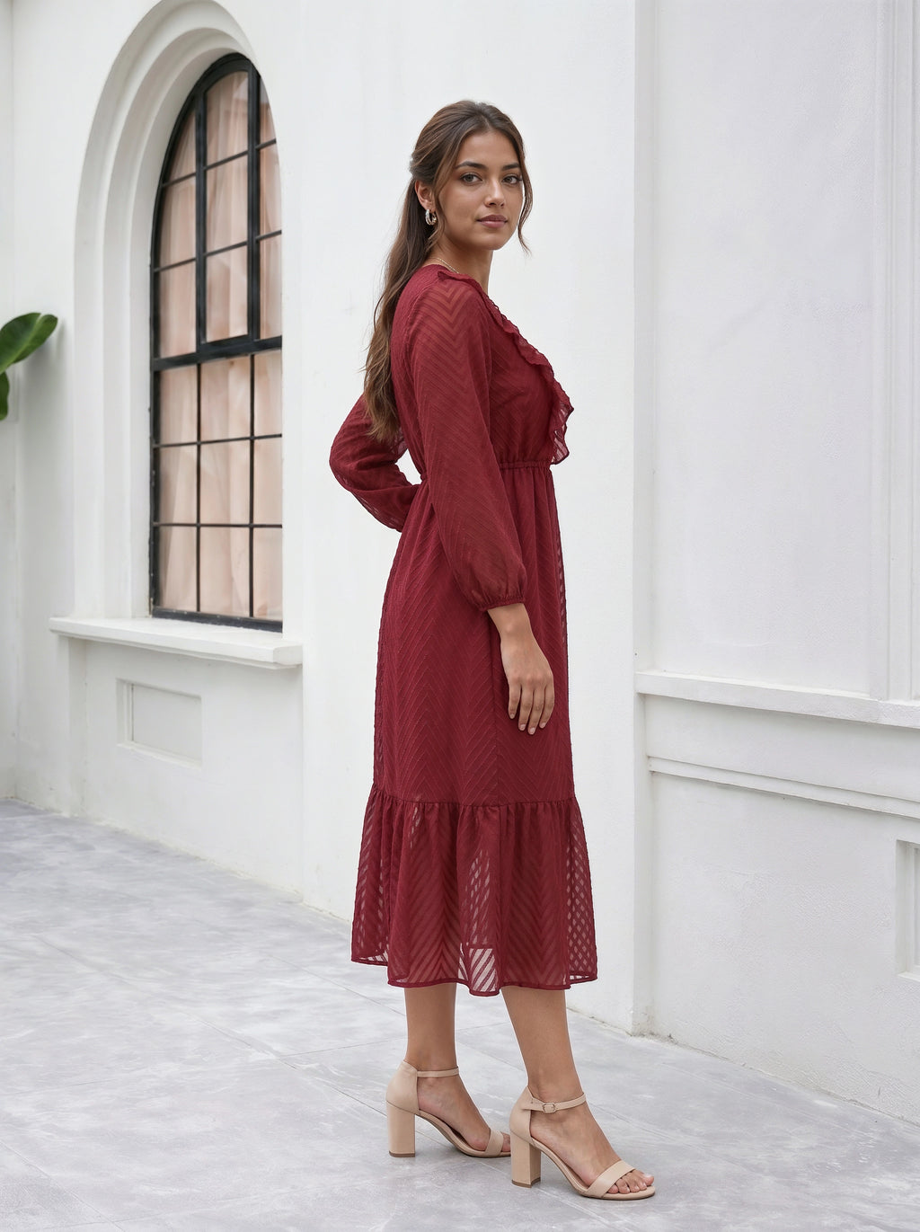 Woman in a red dress standing in a white room with a window.