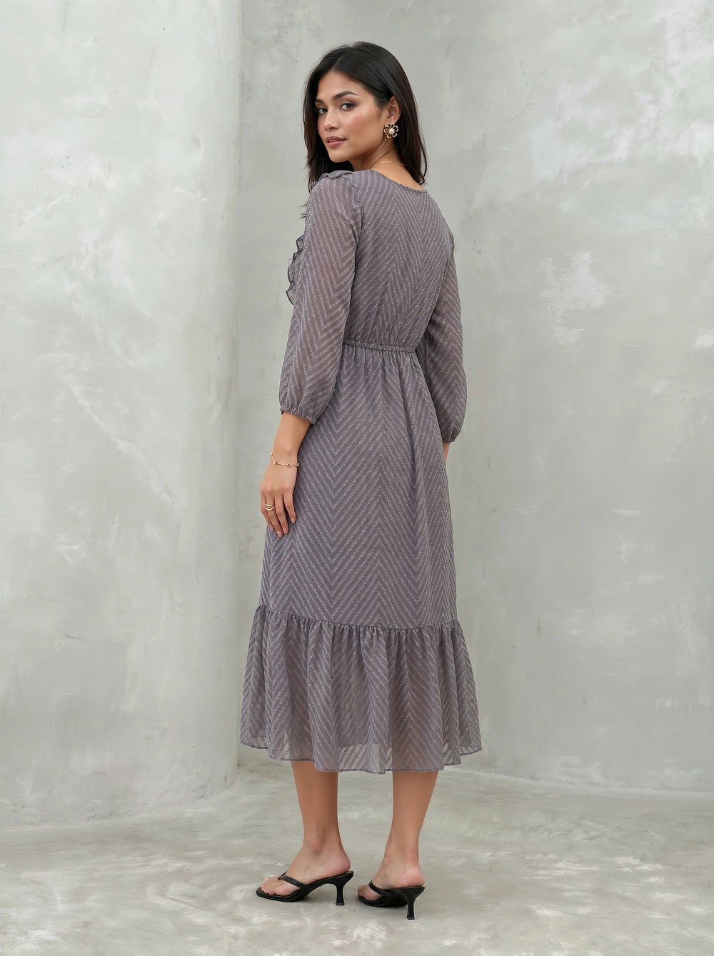 Woman wearing a patterned dress against a plain background