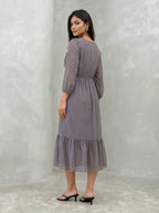 Woman wearing a patterned dress against a plain background