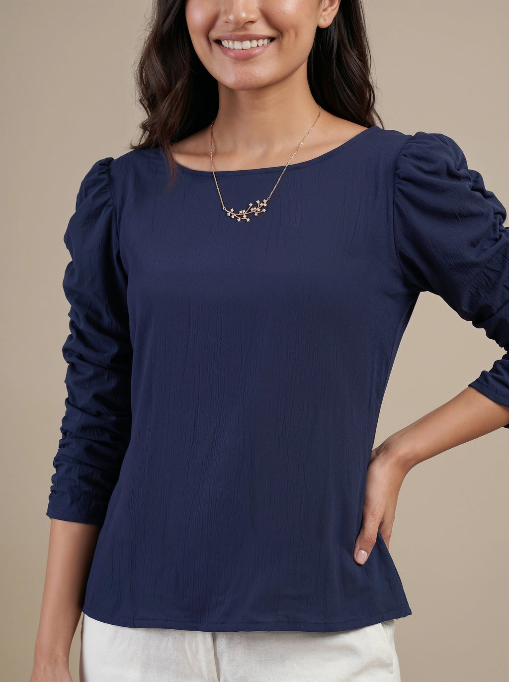 Woman wearing a navy blue long-sleeve top against a beige background