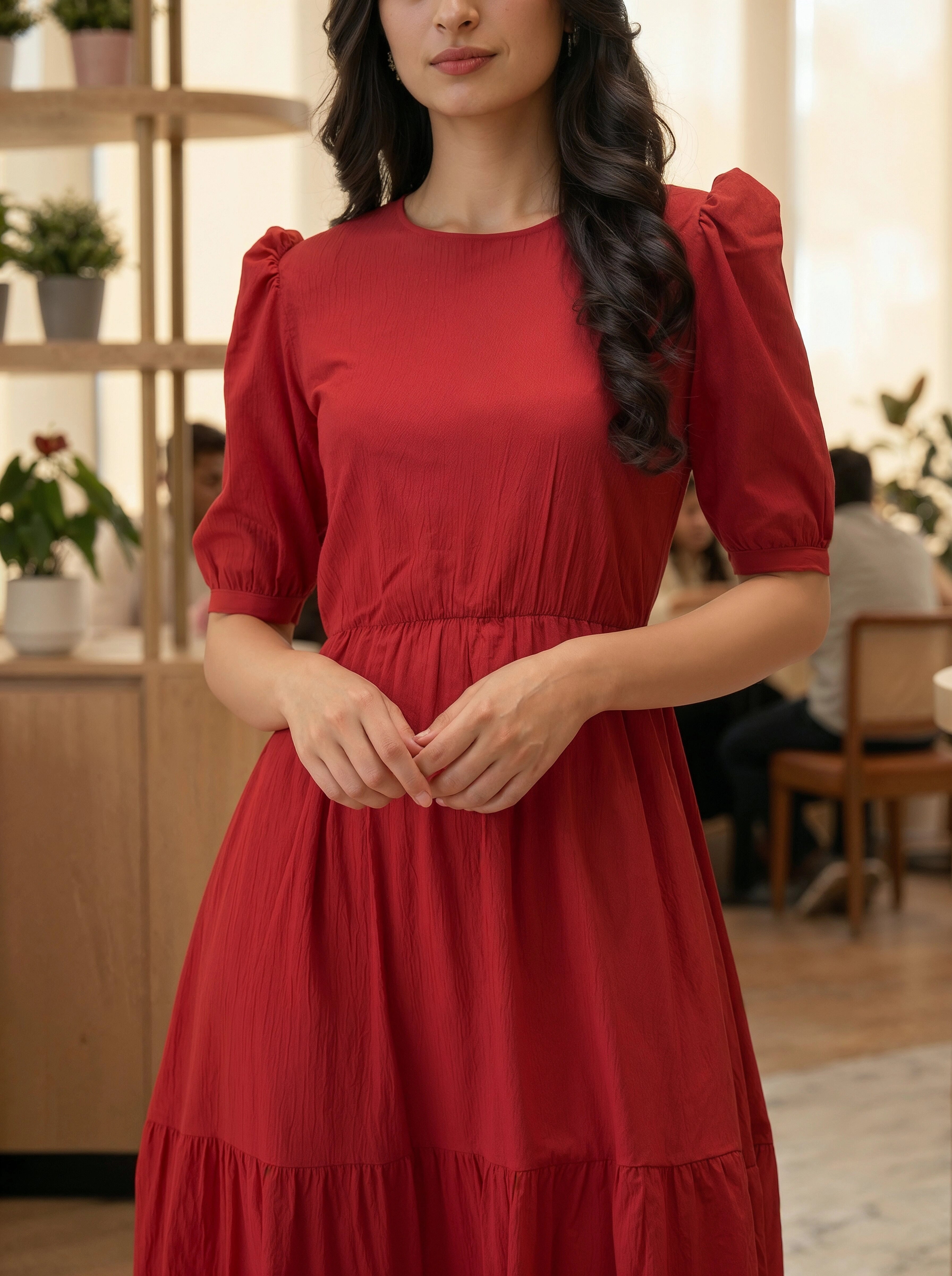 Woman wearing an elegant red midi dress with puff sleeves in a modern indoor setting.