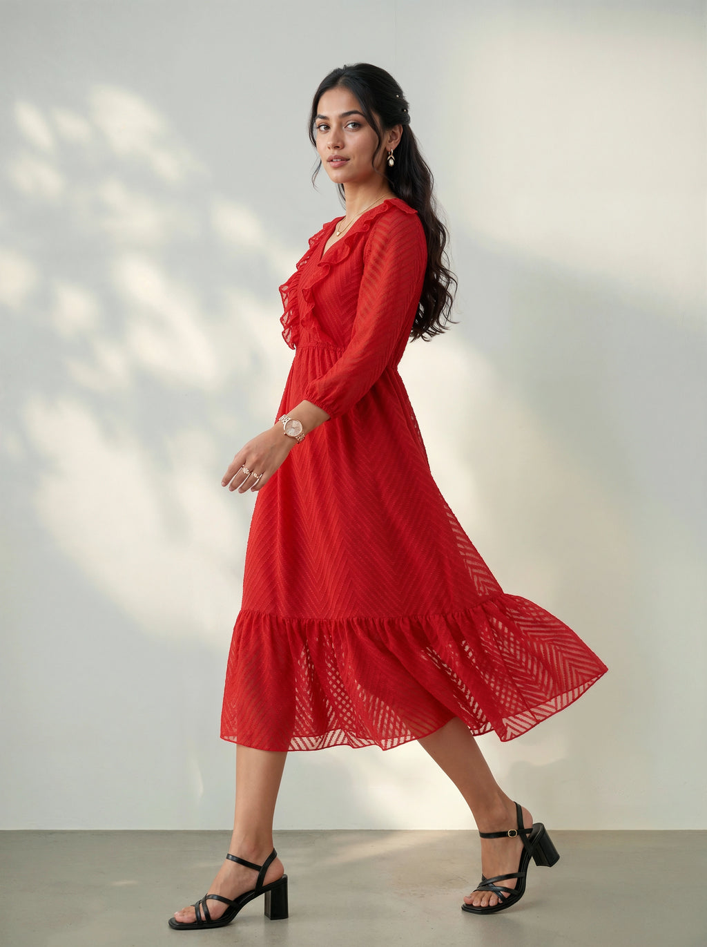 Woman wearing a red dress standing against a plain background