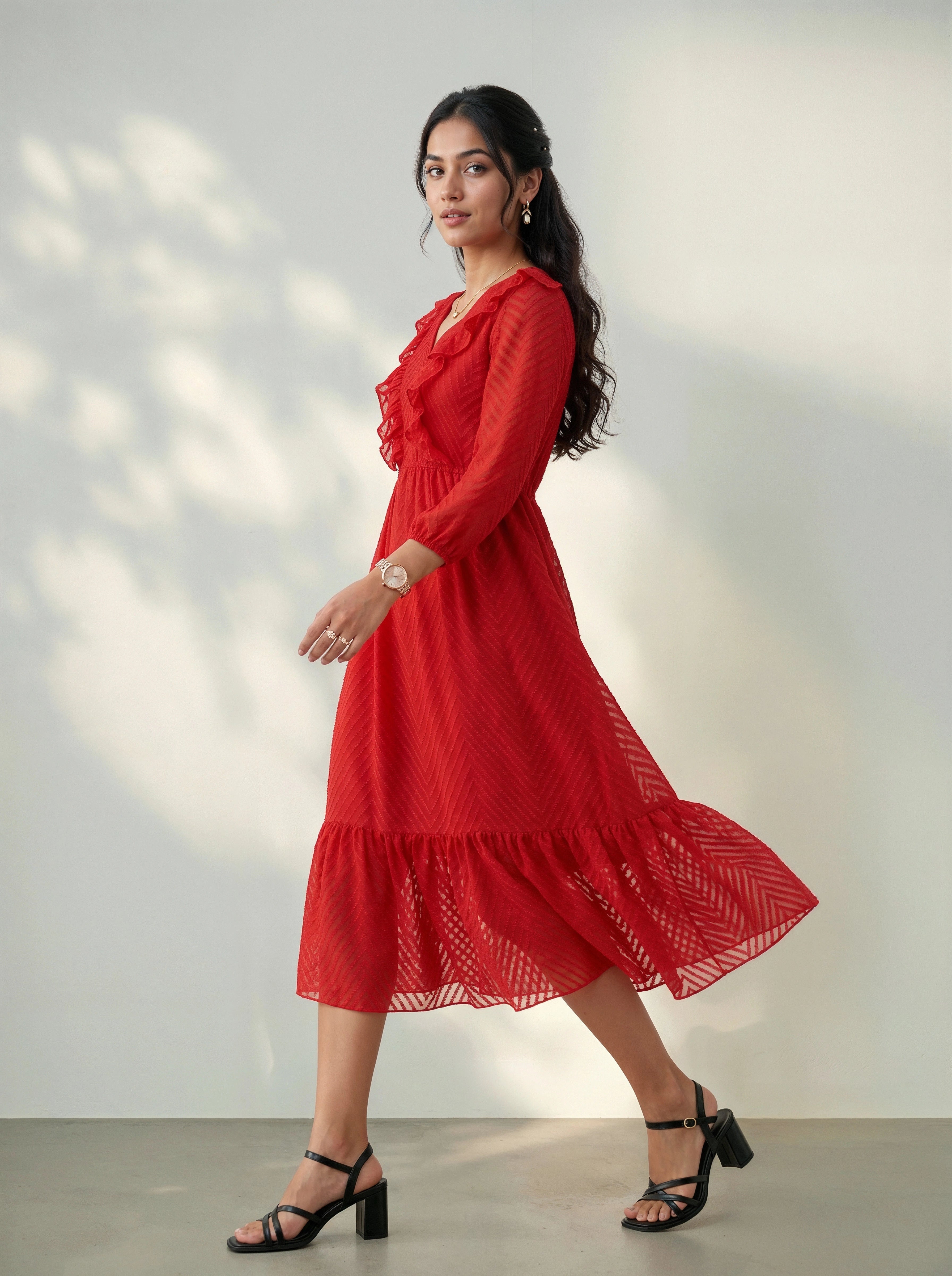 Woman wearing a red dress standing against a plain background