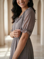 Woman wearing a gray dress with a blurred architectural background