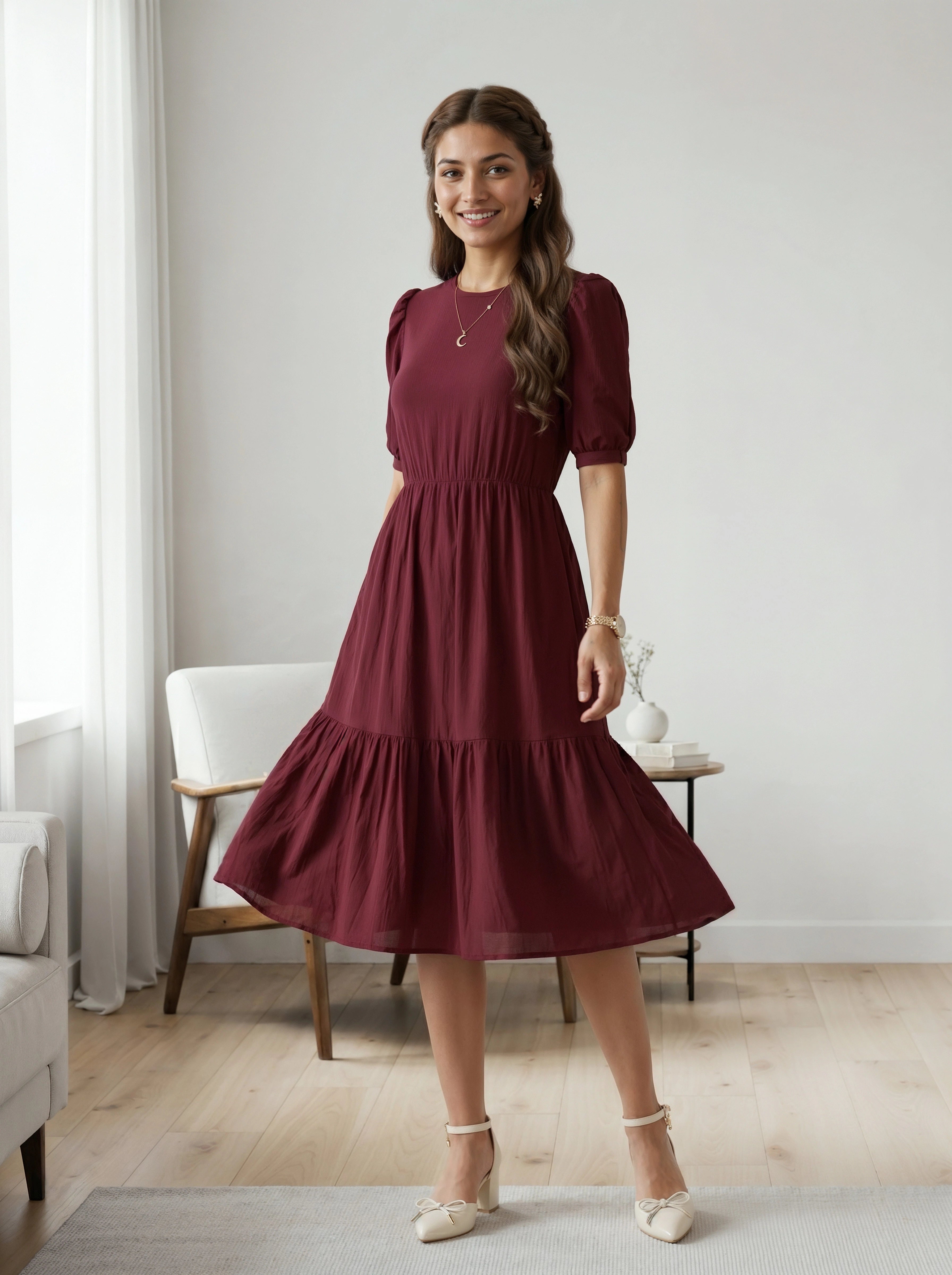 Woman wearing a burgundy dress in a room with a white chair and light-colored walls.