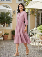 Woman in a pink dress standing outdoors in a garden setting