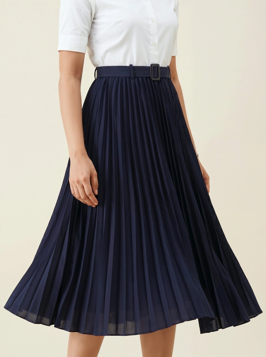 Navy pleated skirt worn with a white top on a beige background