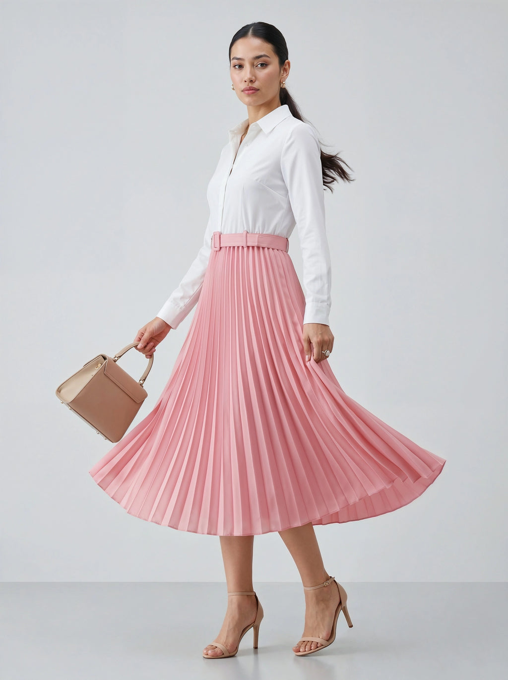 Woman wearing a white blouse and pink pleated skirt holding a beige handbag on a light gray background