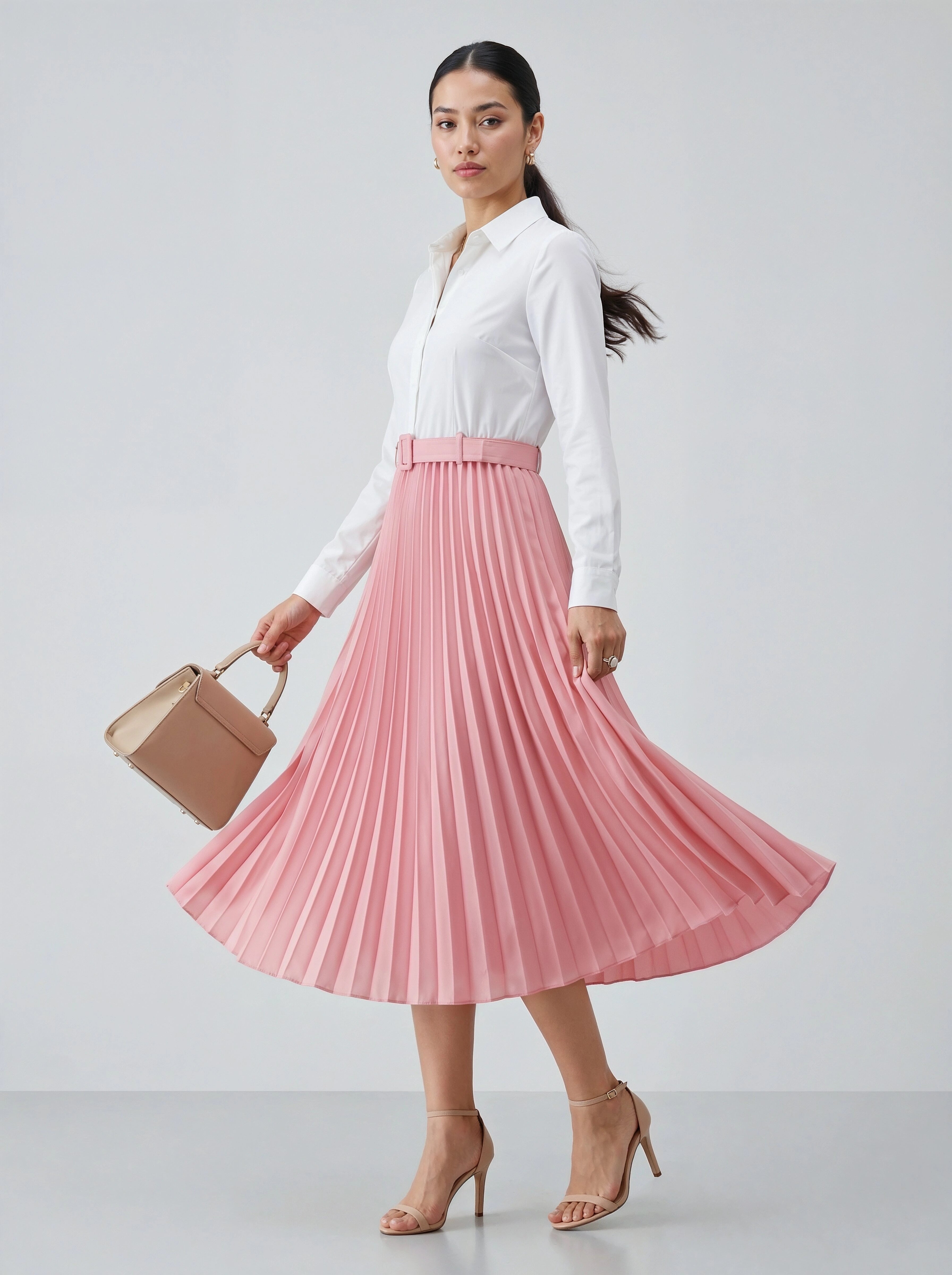 Woman wearing a white blouse and pink pleated skirt holding a beige handbag on a light gray background
