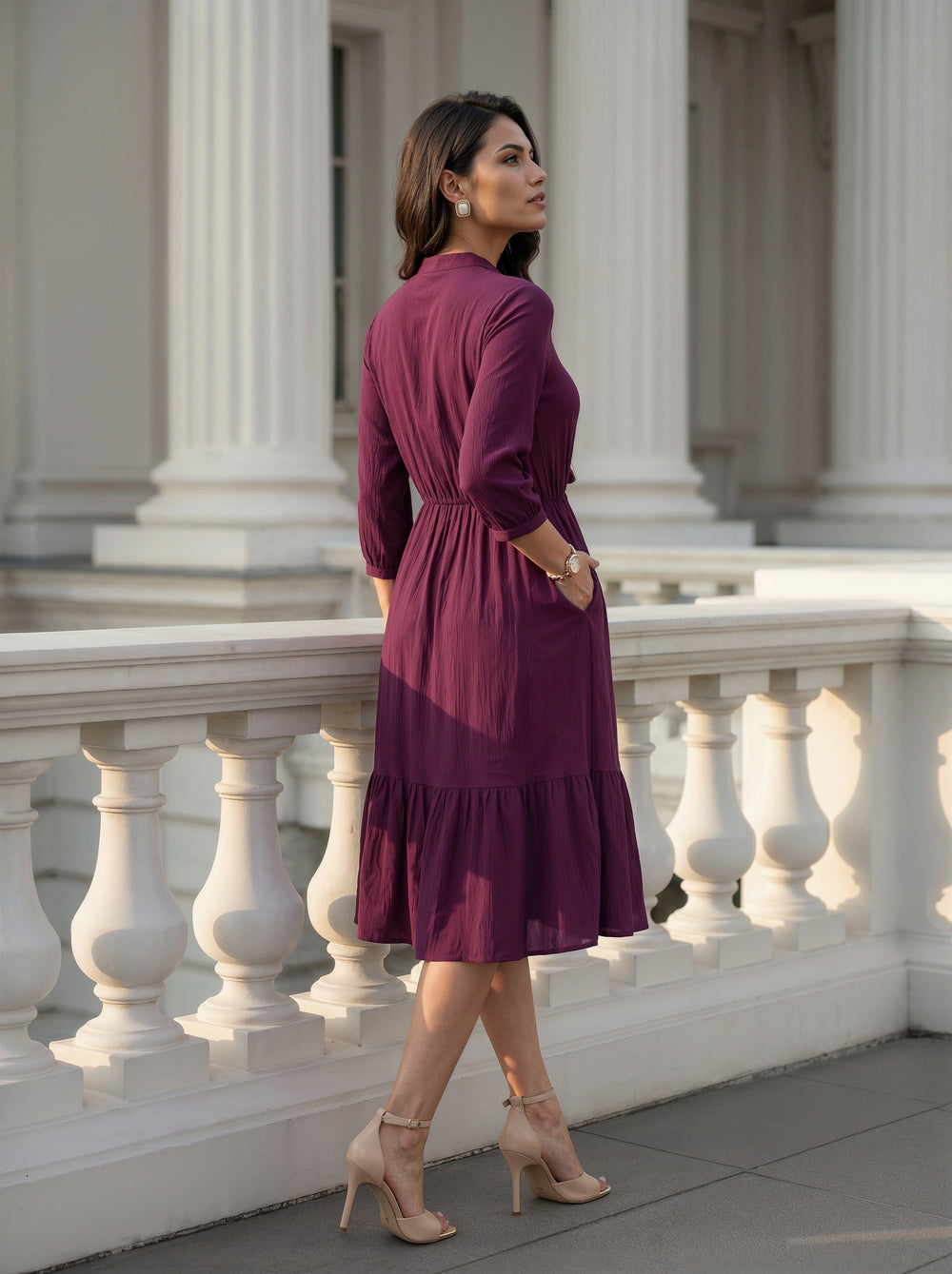Woman in a purple dress standing on a classical building's steps.