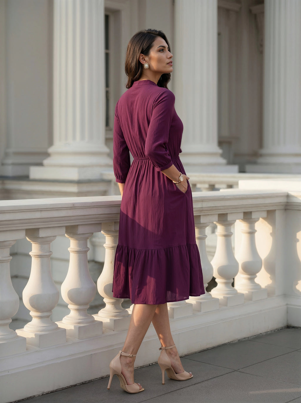 Woman in a purple dress standing on a classical building's steps.