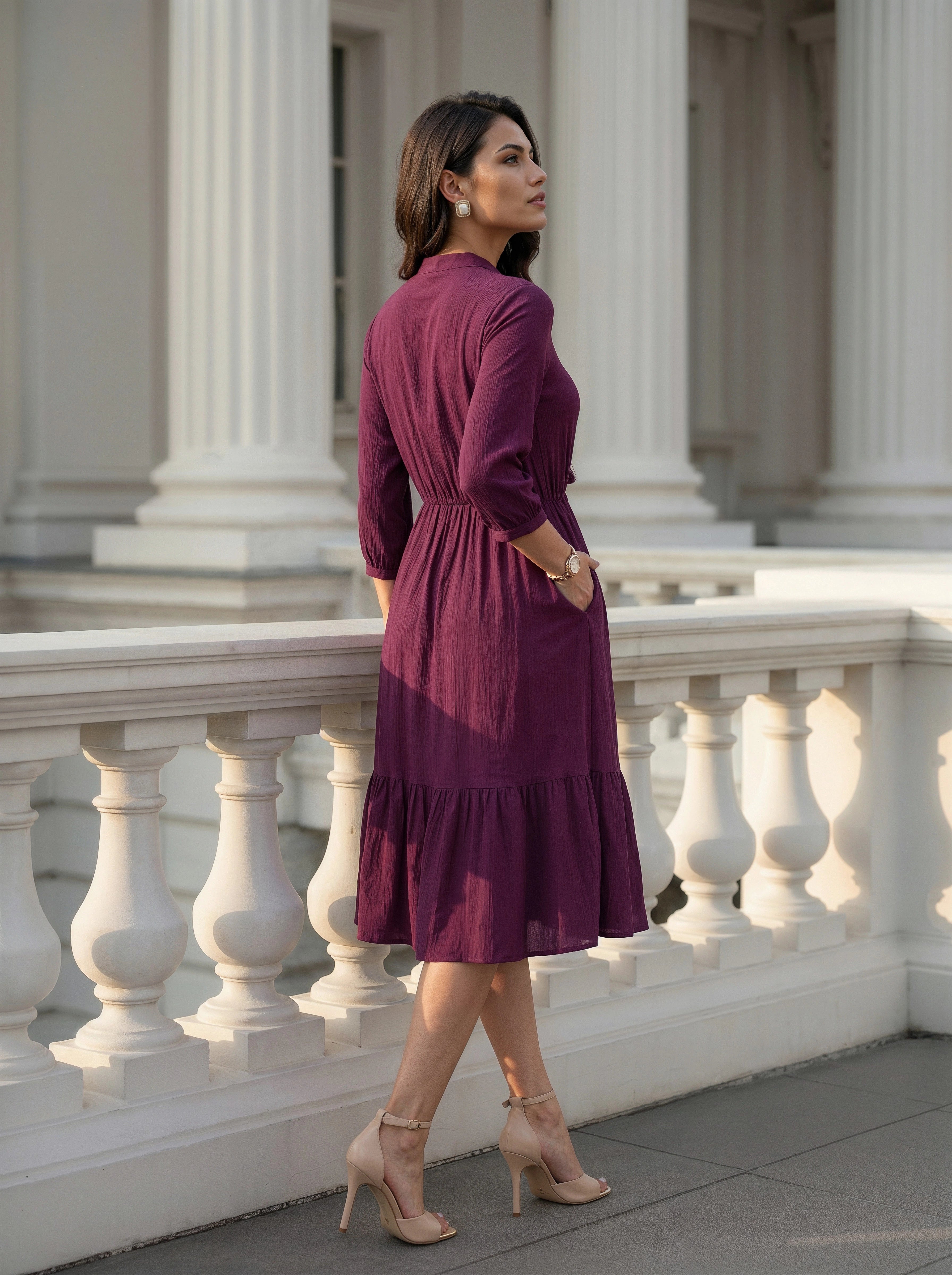 Woman in a purple dress standing on a classical building's steps.