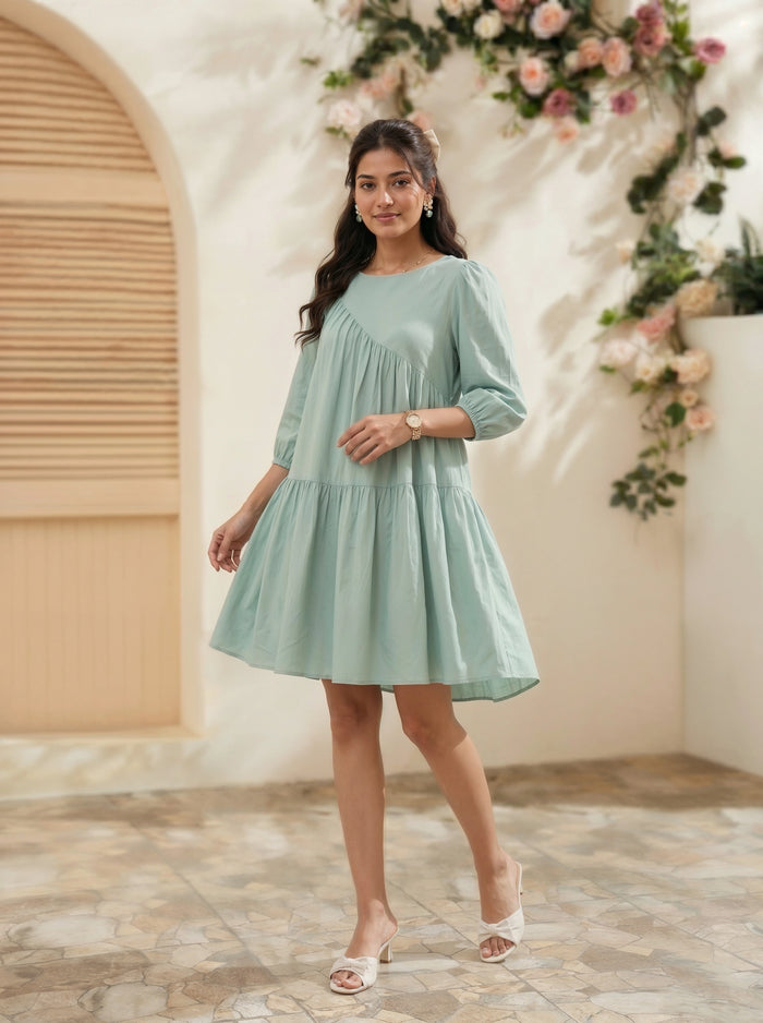 Woman in a light green dress standing in a decorated indoor setting with flowers.