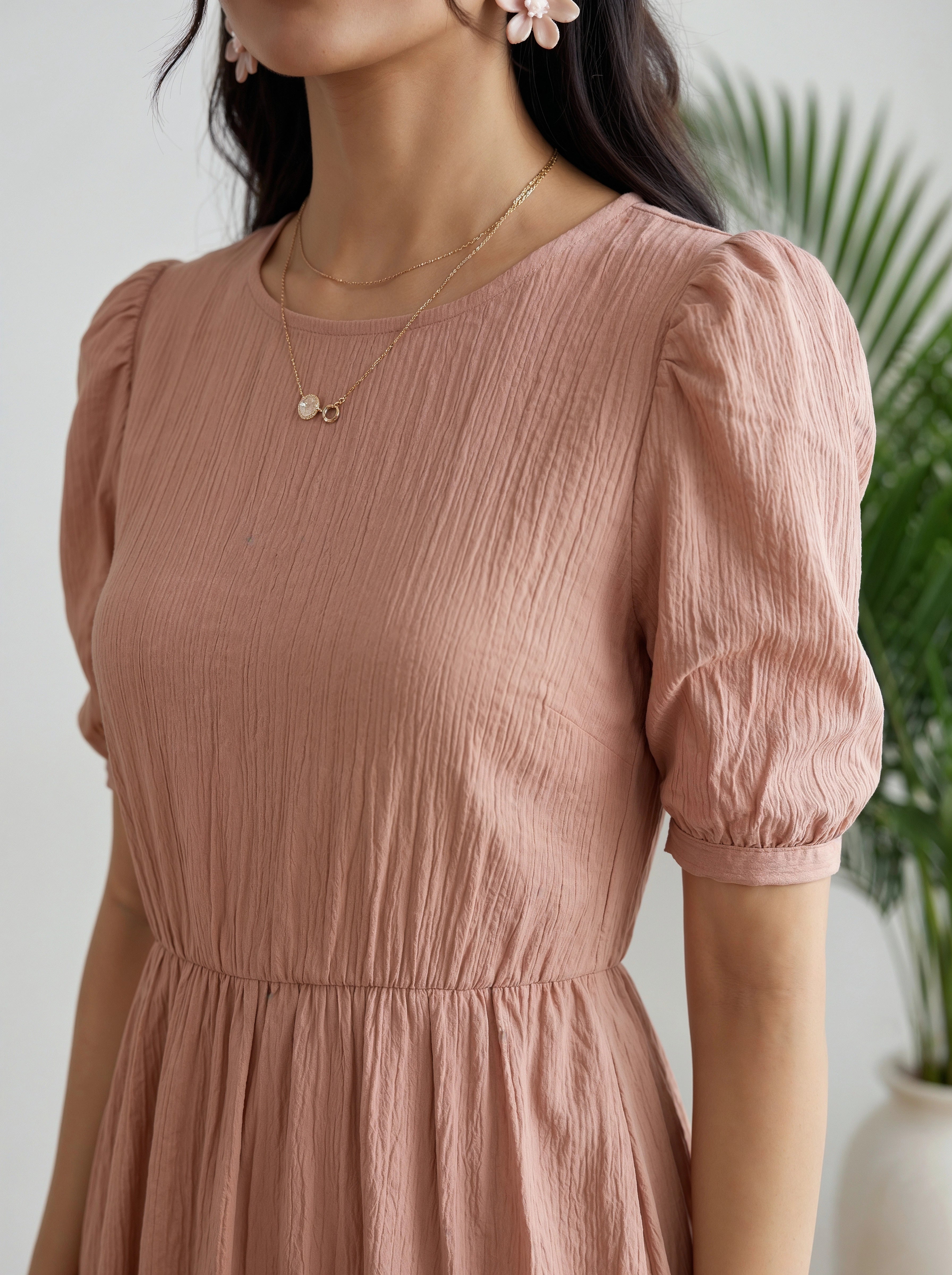 Woman wearing a pink dress with puffed sleeves against a white background