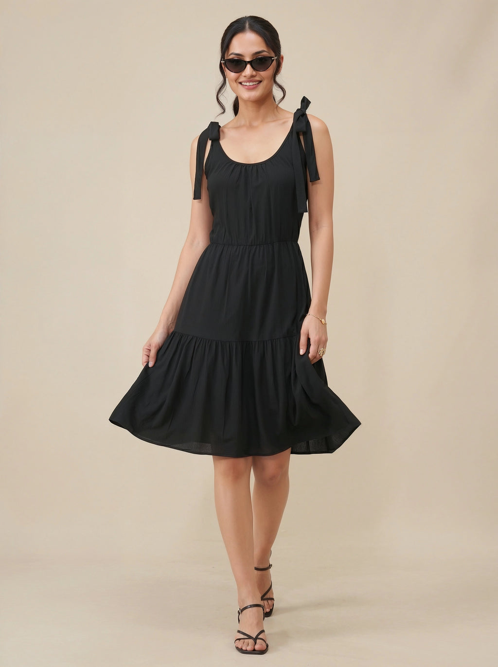 Woman wearing a black dress with bow straps on a beige background