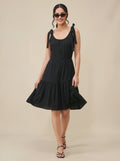 Woman wearing a black dress with bow straps on a beige background
