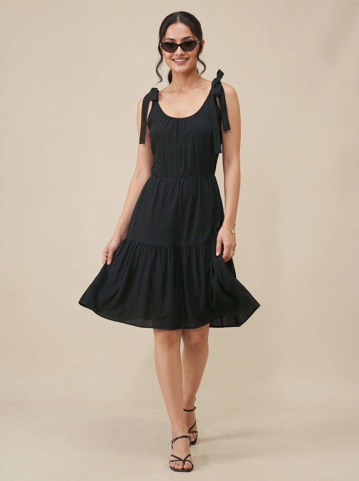 Woman wearing a black dress with bow straps on a beige background