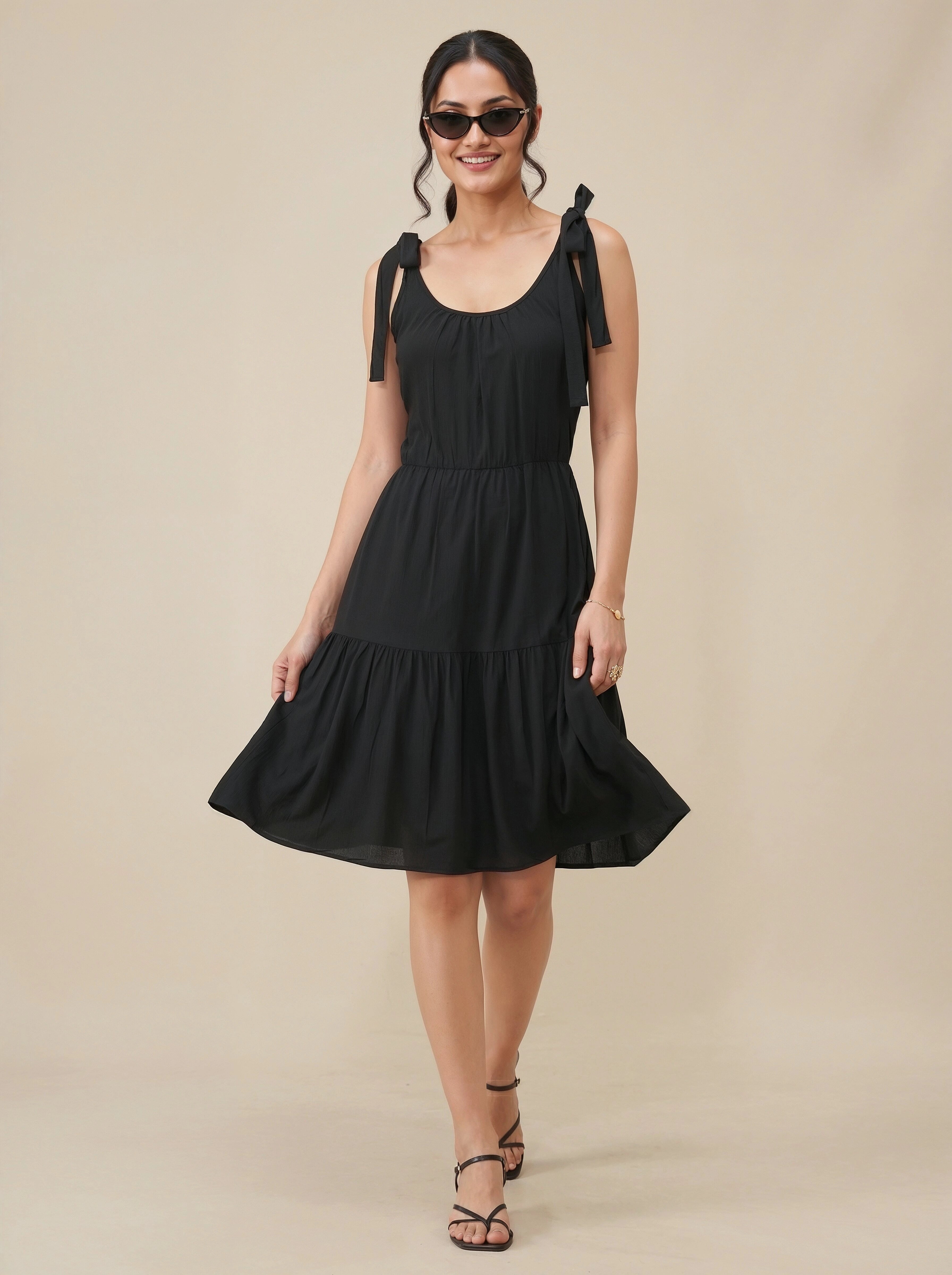 Woman wearing a black dress with bow straps on a beige background