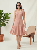 Woman in a pink dress standing next to a plant and chair on a white background