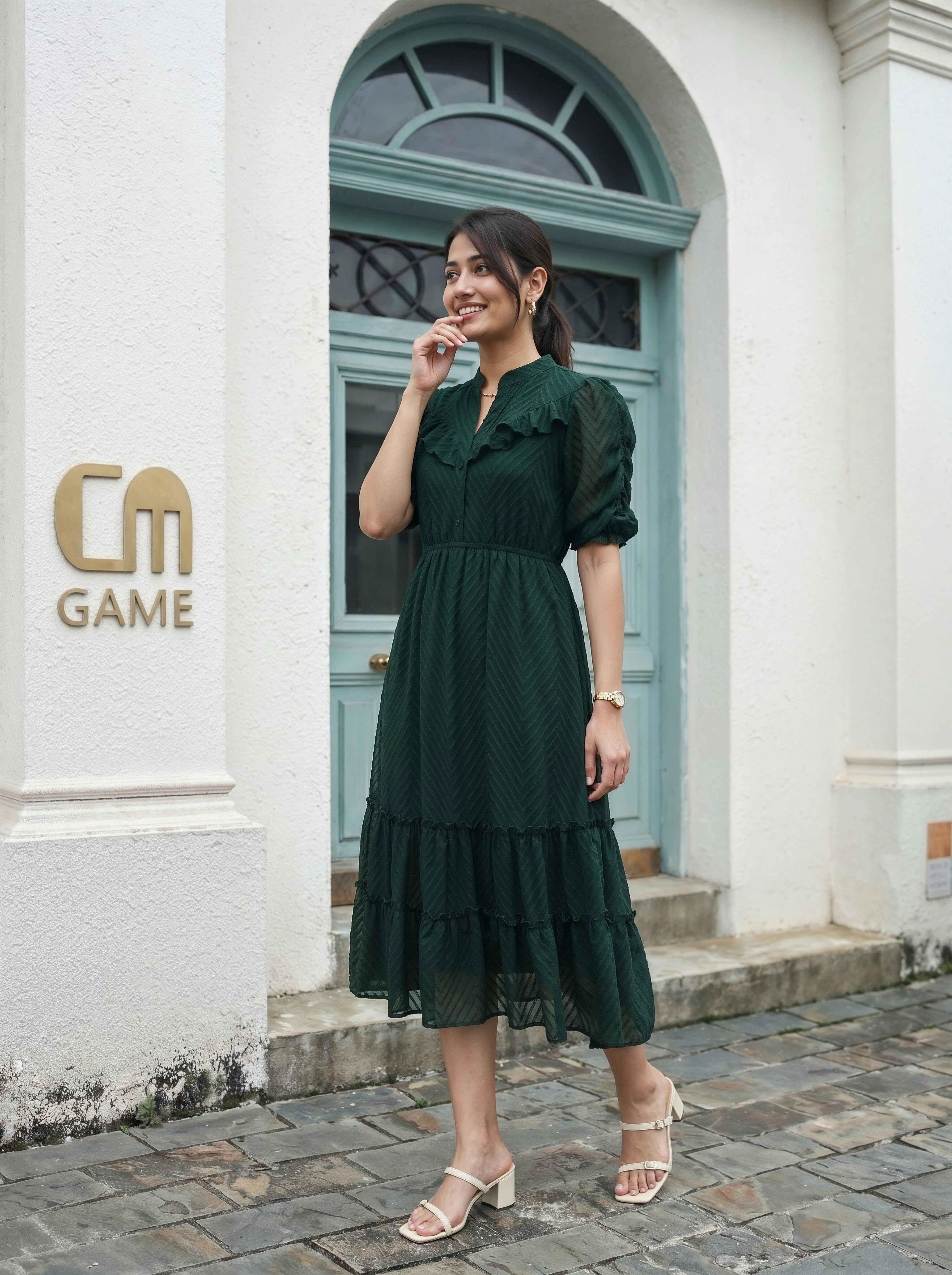 Woman in a green dress standing in front of a building with 'CM Game' logo.