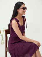 Woman wearing a purple dress sitting on a chair with a white background