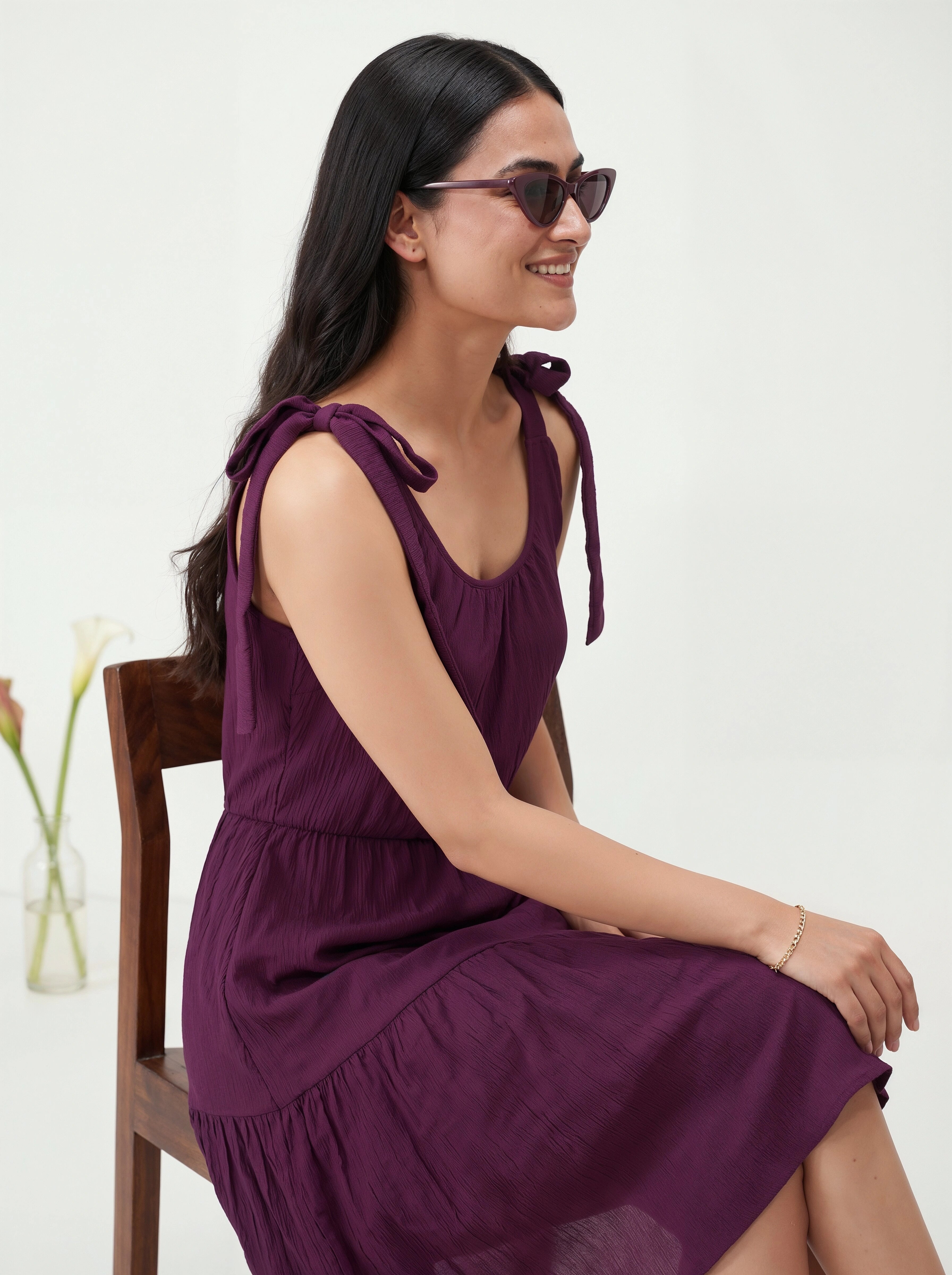 Woman wearing a purple dress sitting on a chair with a white background