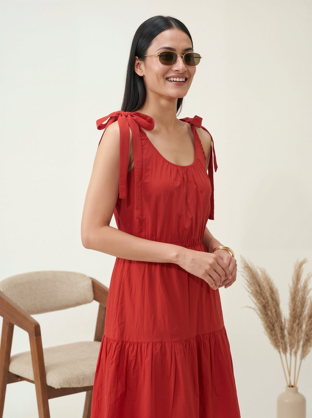 Woman wearing a red dress with bow straps against a neutral background