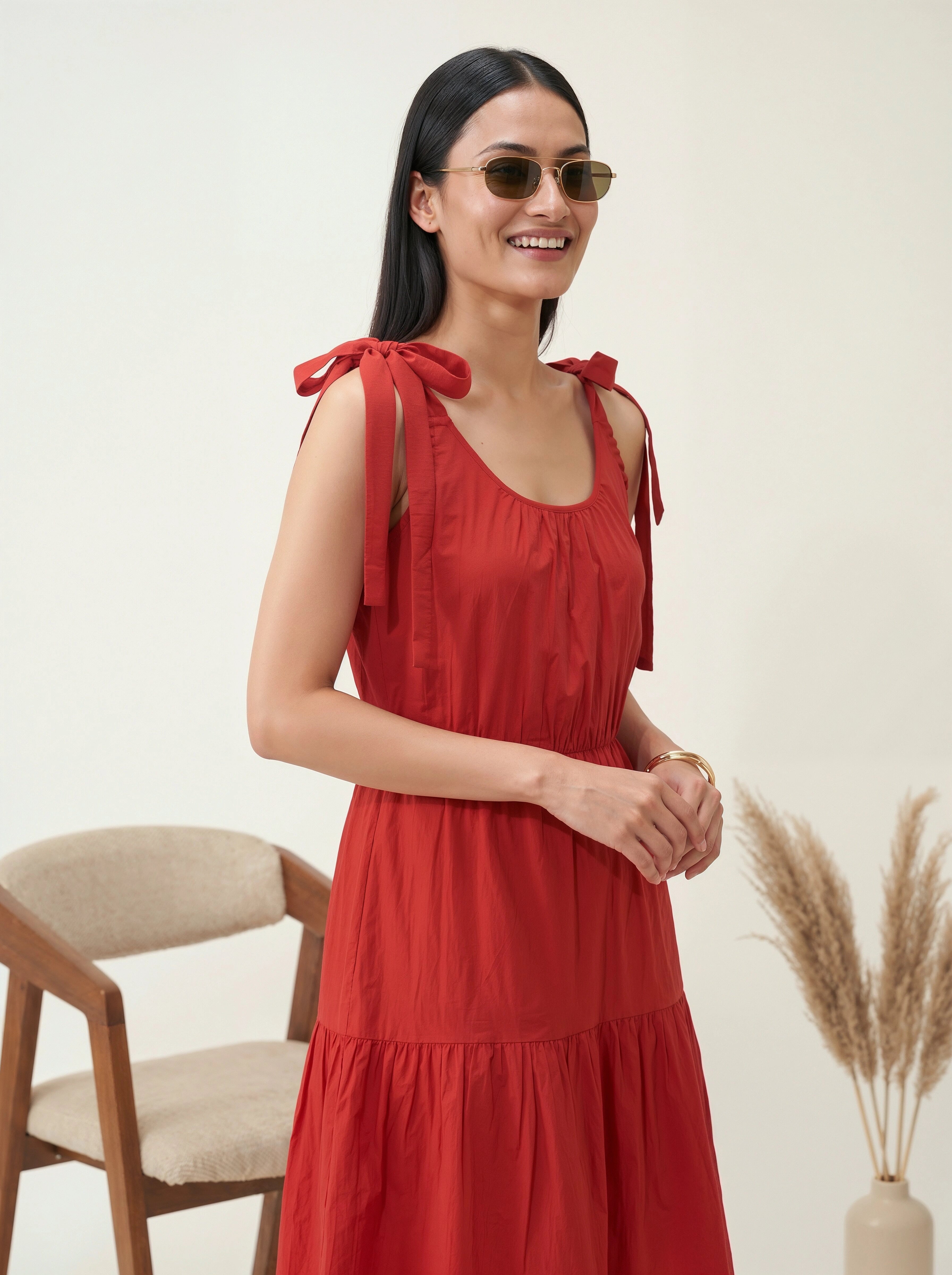 Woman wearing a red dress with bow straps against a neutral background
