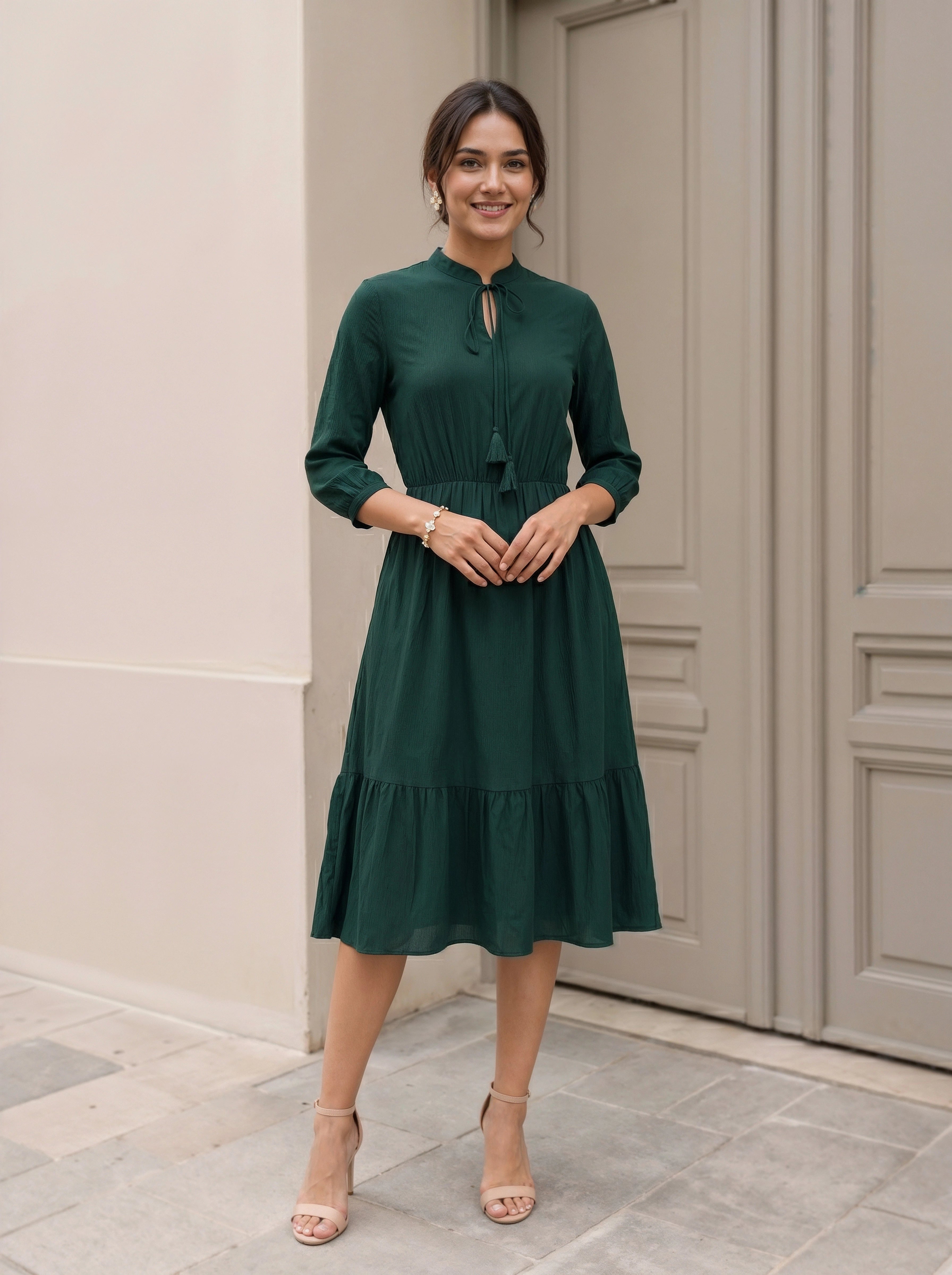 Woman wearing a green dress standing in front of a door.